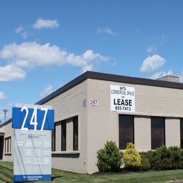 Exterior photo of 247 Cayuga Road during the day showing a tan building.  The sky is blue with clouds.